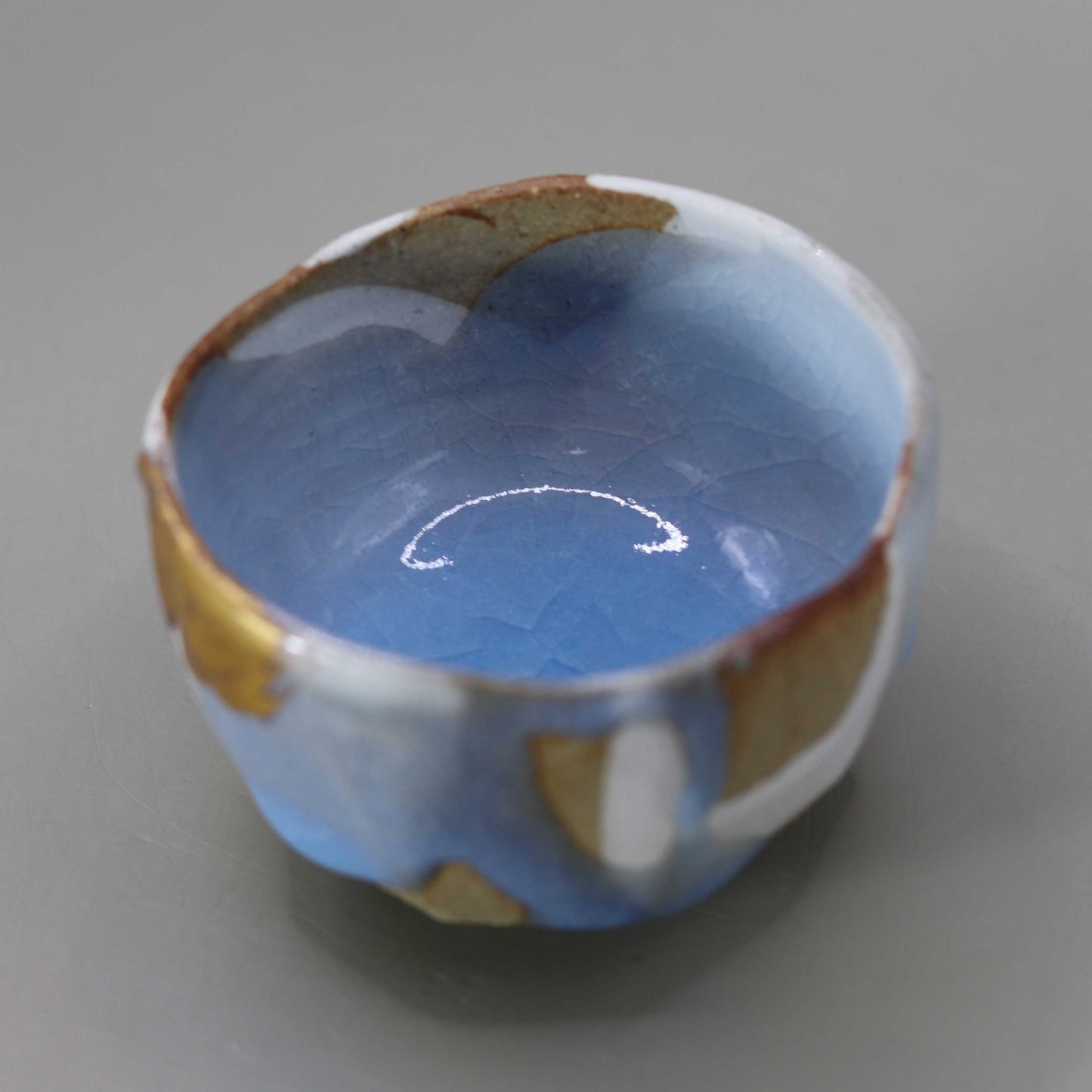 Sake cup with moon-white glaze and gold leaf by Matsubayashi Hosai