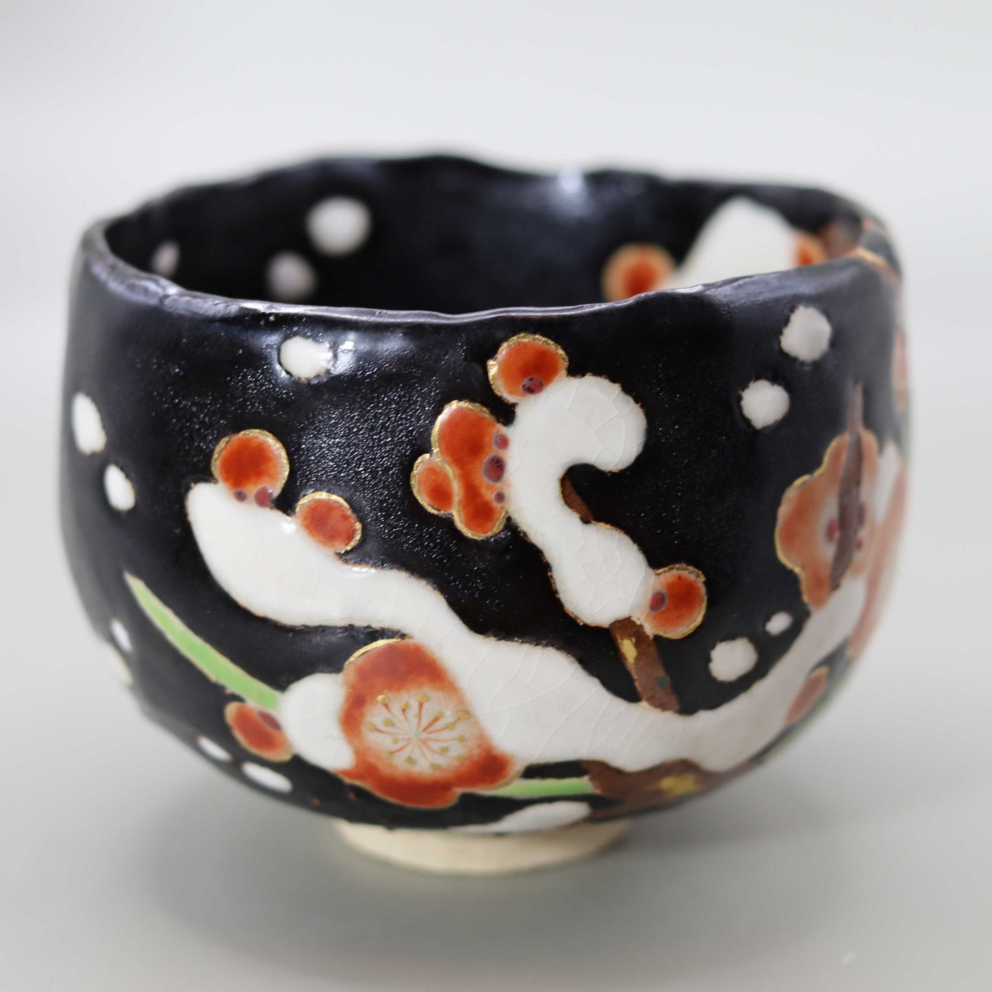 Raku tea bowl decorated with plum blossoms in the snow by Miyagawa Kosai