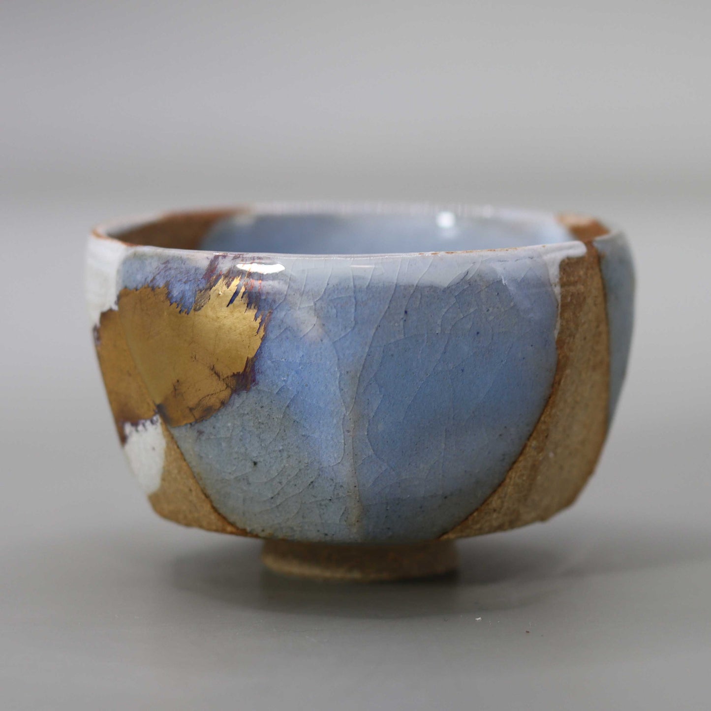 Sake cup with moon-white glaze and gold leaf by Matsubayashi Hosai