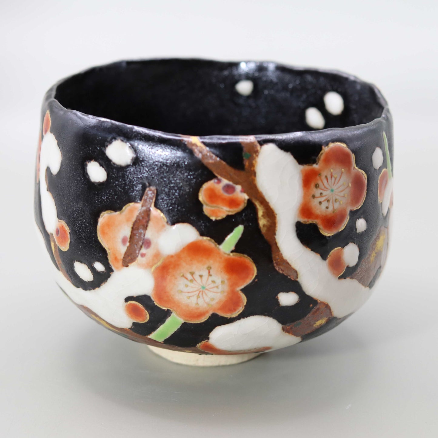 Raku tea bowl decorated with plum blossoms in the snow by Miyagawa Kosai